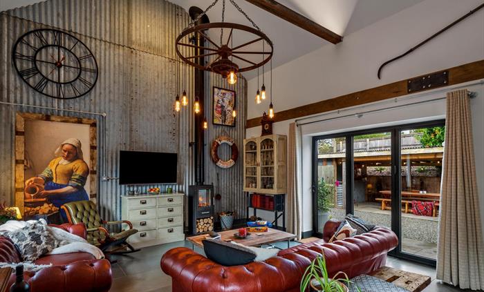 Lounge with Chesterfield sofas, wood burning stove, smart TV, bi-fold door to covered outside patio, BBQ area. Corrogated iron (Zinc) feature wall, ru
